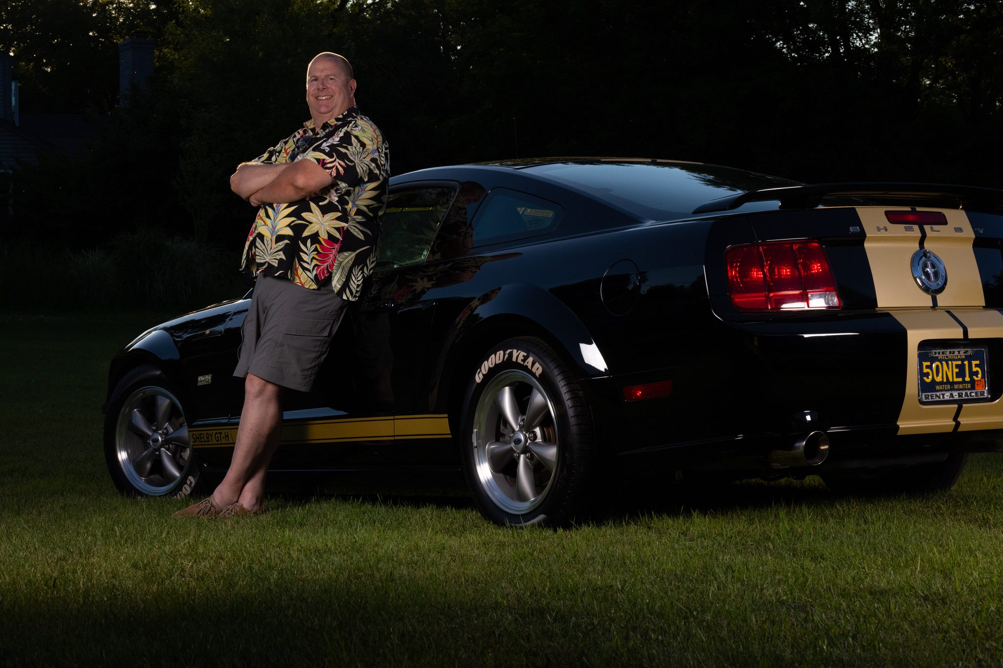 Golden-hour portrait of a collector leaning on a Shelby GT-H Mustang on the lawn — fine art portraiture, Southeast Michigan