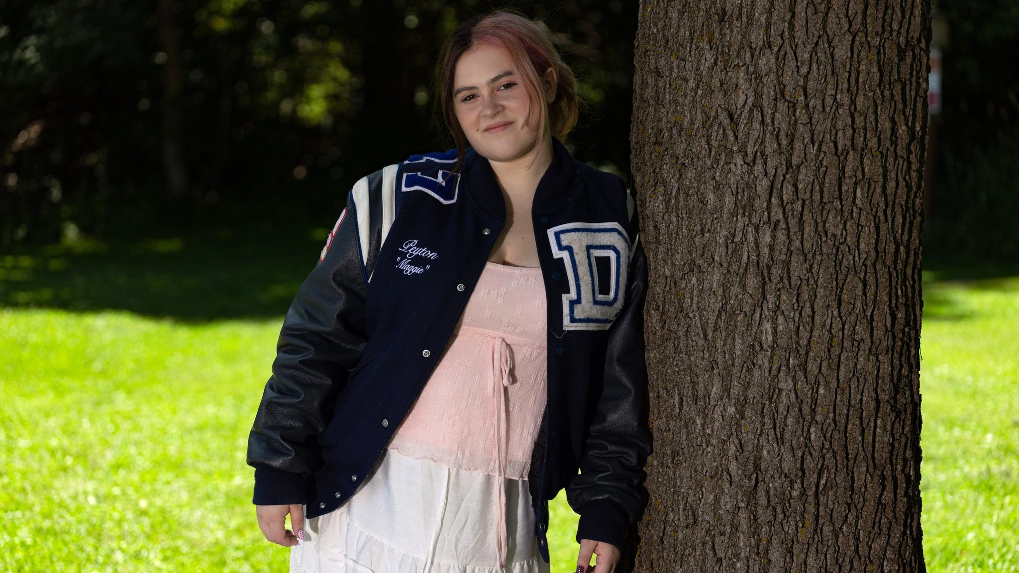 High school senior in letterman jacket by a tree — Ann Arbor senior portrait example
