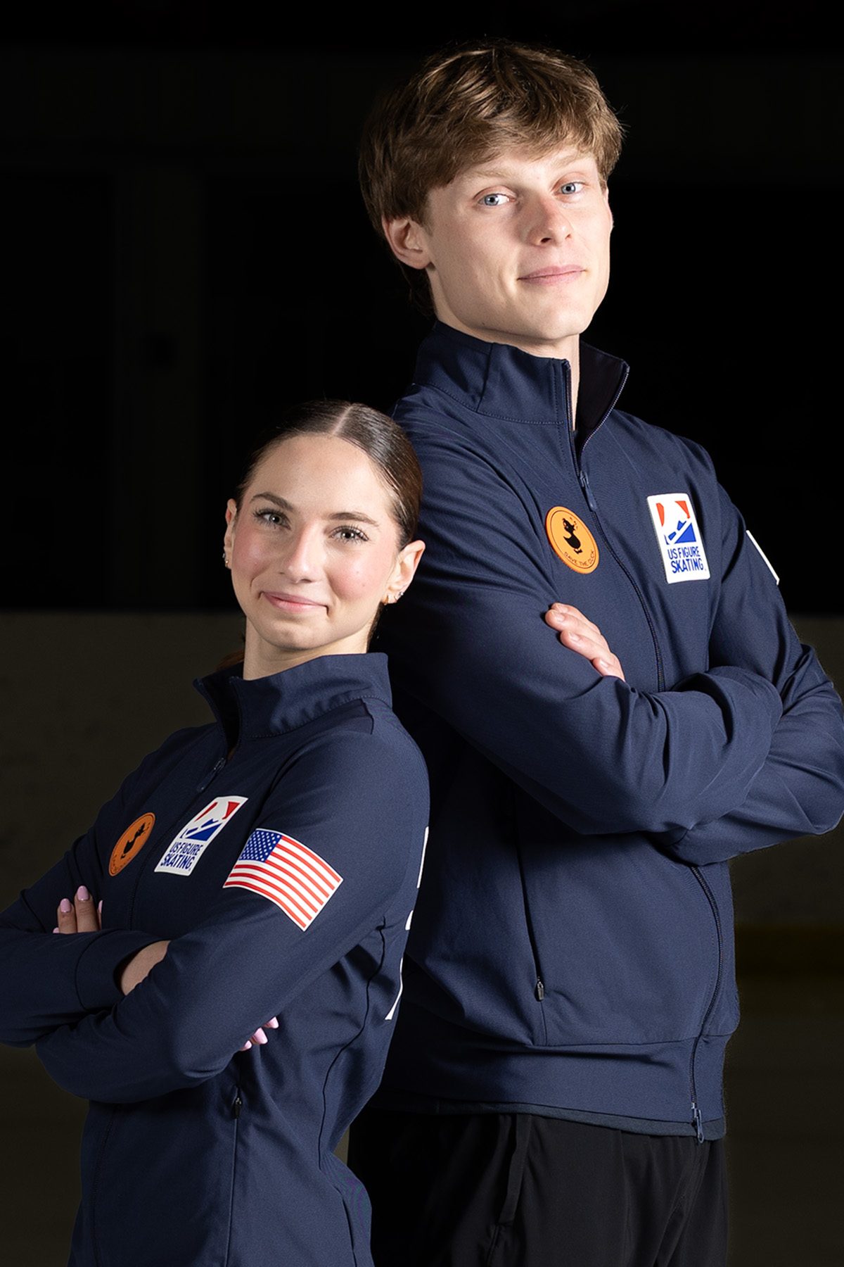 Close portrait of a figure skating pair, partner's arms raised behind — fine art sports portraiture, Ann Arbor