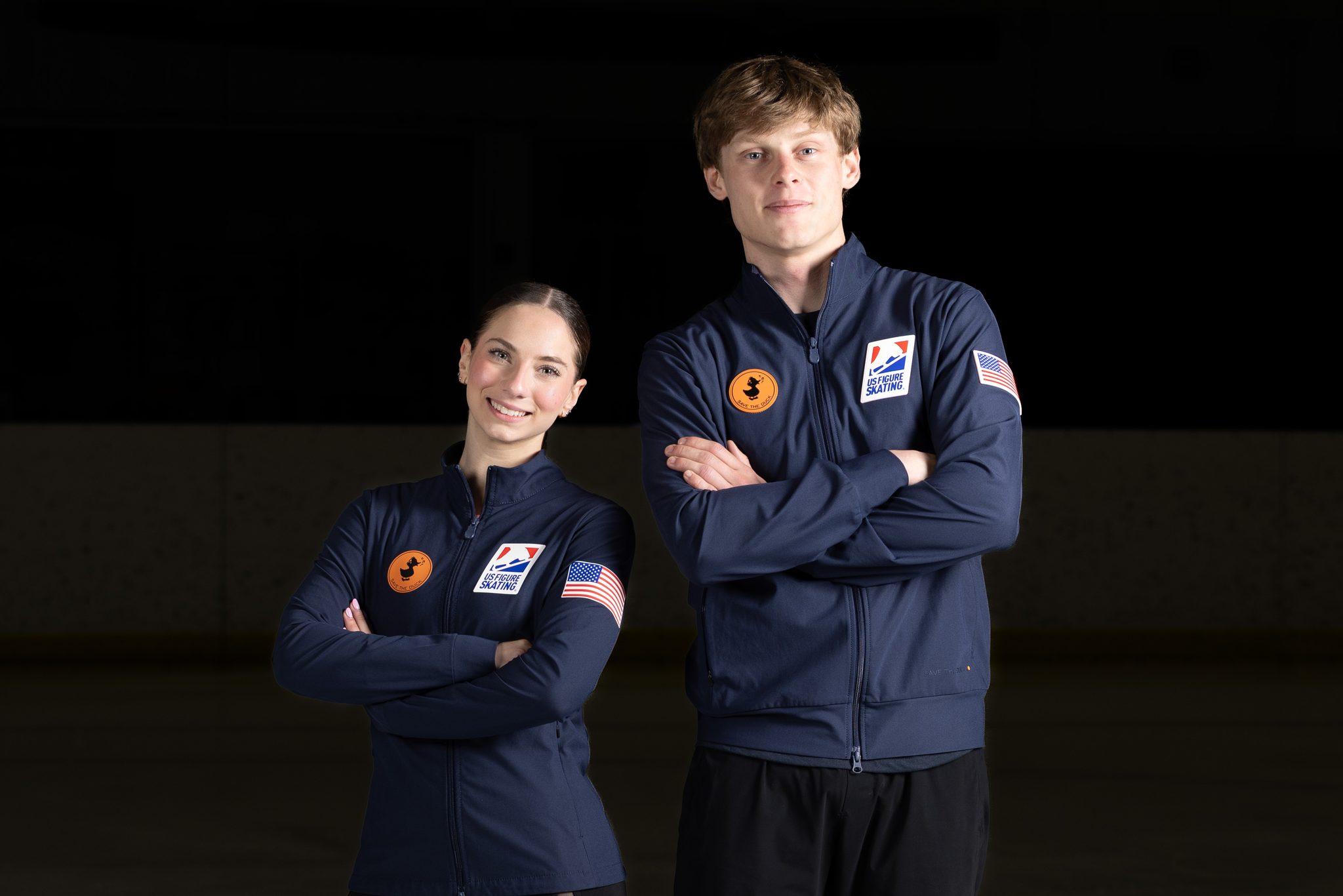 Figure skating pair portrait with arms crossed, studio lighting on the ice — Ann Arbor athlete photography