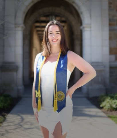 Ann Arbor graduation portrait of Sam in a white dress and Michigan M stole, framed by a Gothic sandstone archway in the University of Michigan Law Quad